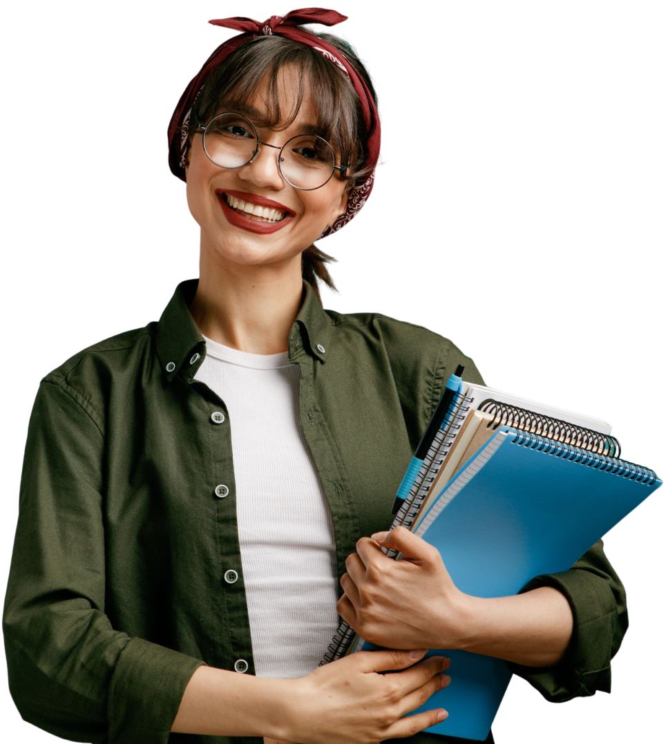 A imagem mostra uma mulher jovem branca de óculos, com franja e cabelo escuro preso, sorrindo enquanto segura alguns cadernos